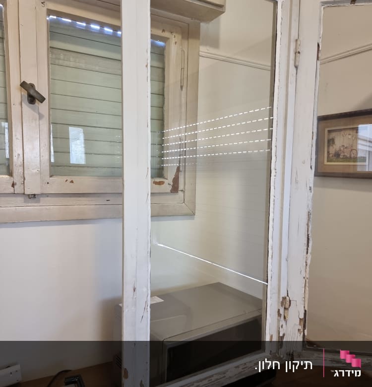 חלון זכוכית עם מסגרת עץ מתקלפת